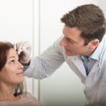 Das Bild steht für Botox Preise Wien. Es zeigt eine Szene im Dermacare Institut in Wien. Ein Arzt oder ein medizinischer Fachmann in einem weißen Kittel ist dabei, einer Patientin, die auf einem Behandlungsstuhl sitzt, eine Markierung auf der Stirn zu setzen. Dies ist eine Vorbereitung für eine Botox-Behandlung. Der Arzt trägt Einweghandschuhe und hält einen speziellen Stift, mit dem er präzise Markierungen auf der Stirn der Patientin setzt.