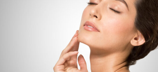 Auf dem Bild sieht man eine entspannte Frau, die mit leicht nach oben geneigtem Kopf und einer Hand sanft ihren Kinnbereich berührt. Ihr klarer, straffer Kieferbereich deutet darauf hin, dass sie eine Doppelkinn entfernen Behandlung bei Dermacare Wien erhalten hat. Ihr zufriedener Ausdruck zeigt, wie effektiv solche Behandlungen sein können, wenn man das Doppelkinn loswerden möchte. Dermacare Wien bietet dafür moderne Methoden wie CoolSculpting, Fettwegspritze und Radiofrequenz Microneedling an, um ein definiertes und harmonisches Gesichtsprofil zu erreichen.